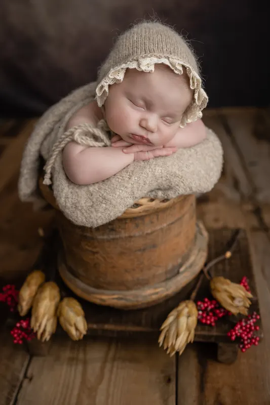 Baby mit Häkelmütze schläft in einem Korb