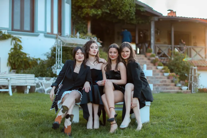 Drei Frauen in eleganten Kleidern sitzen auf einer Treppe