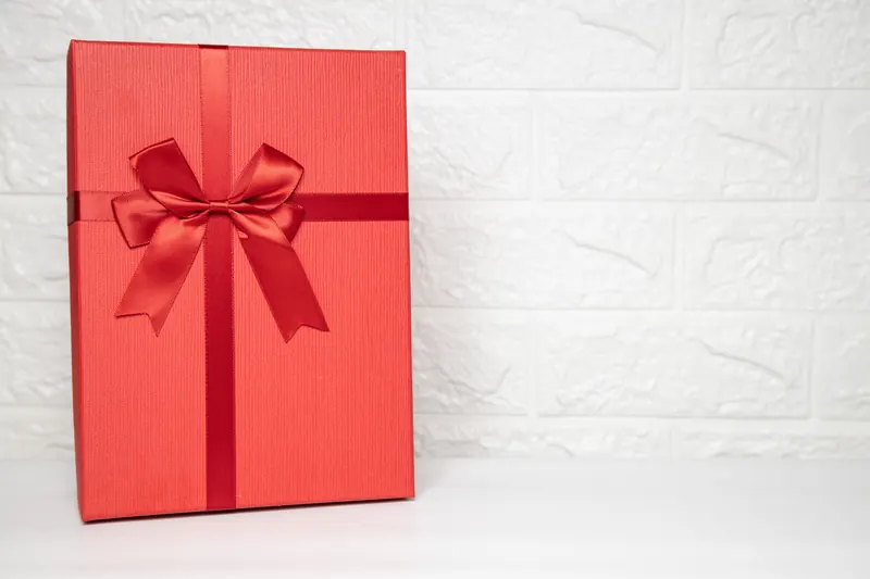 Rote Geschenkbox mit Schleife vor hellem Hintergrund