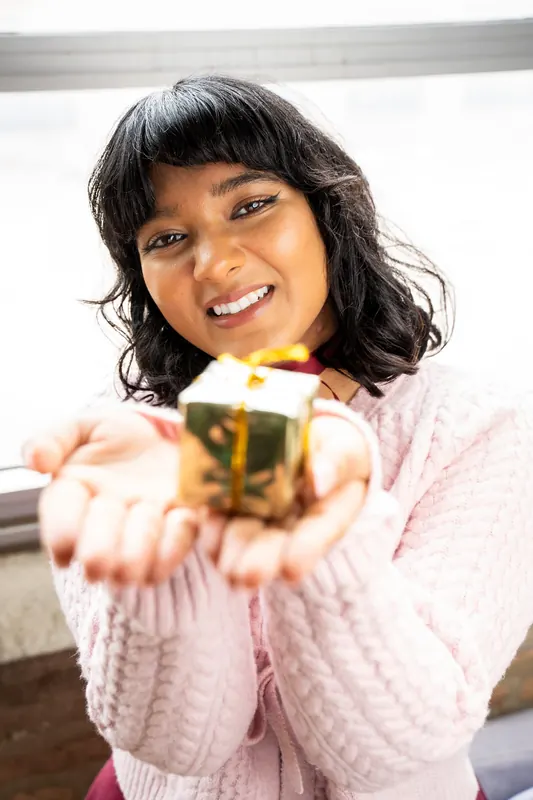 Frau hält ein kleines goldenes Geschenk in der Hand
