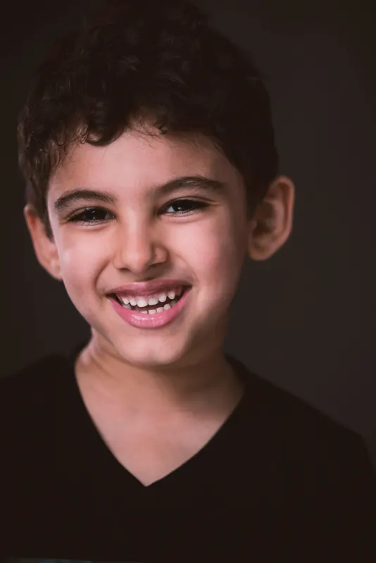 Lächelnder Junge vor dunklem Hintergrund im Fotostudio
