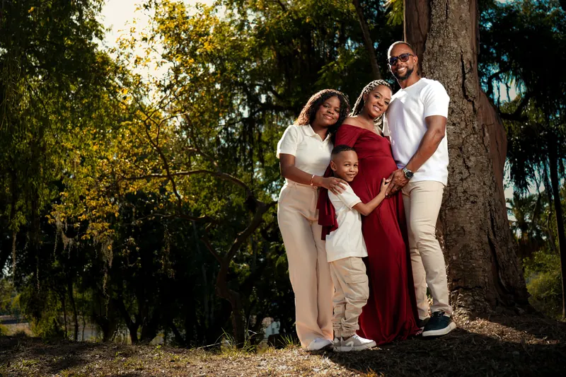 Familie steht lächelnd zwischen herbstlichen Bäumen
